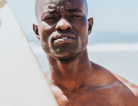 Man standing by the ocean holding surf board
