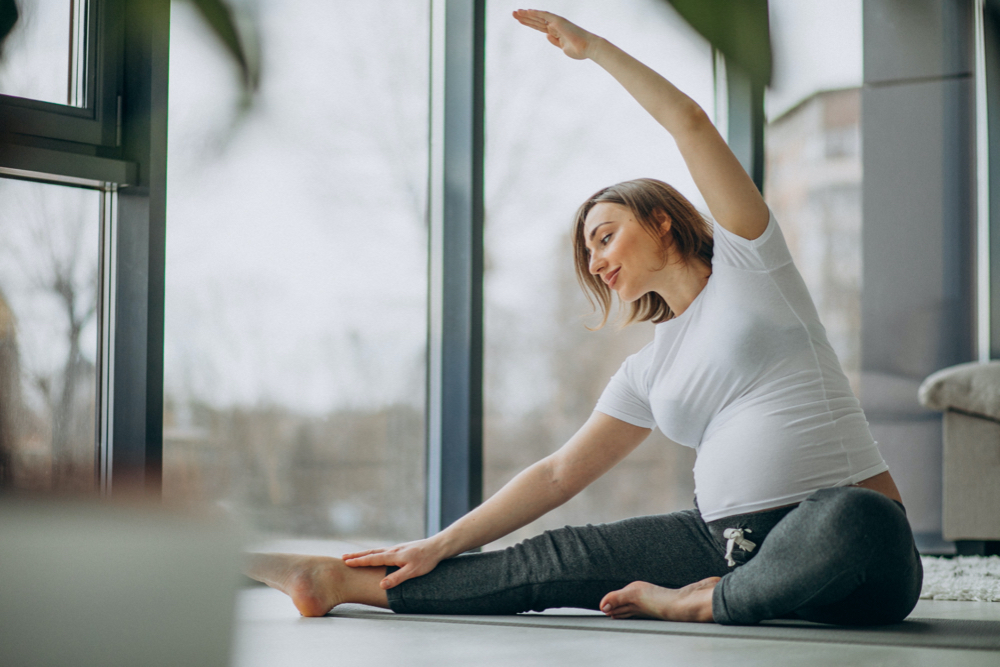 Young pregnant woman practicing yoga at home