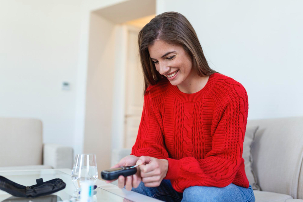 photo woman using lancelet on finger woman doing blood sugar test at home in a living room