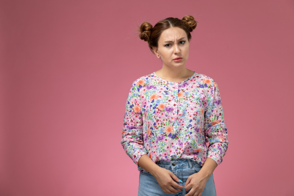 photo front view young female in flower designed shirt and blue jeans just posing on the pink background

