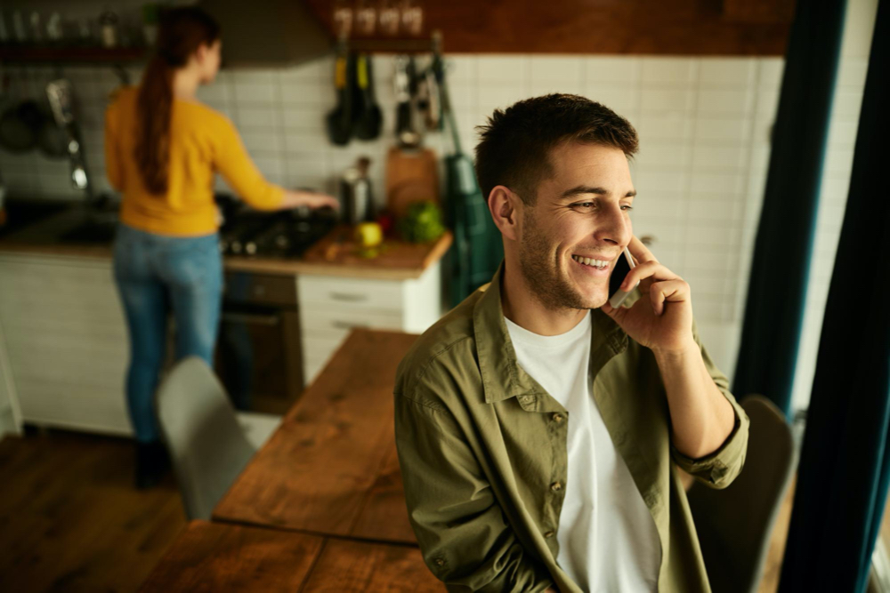 photo young happy man talking on cell phone at home