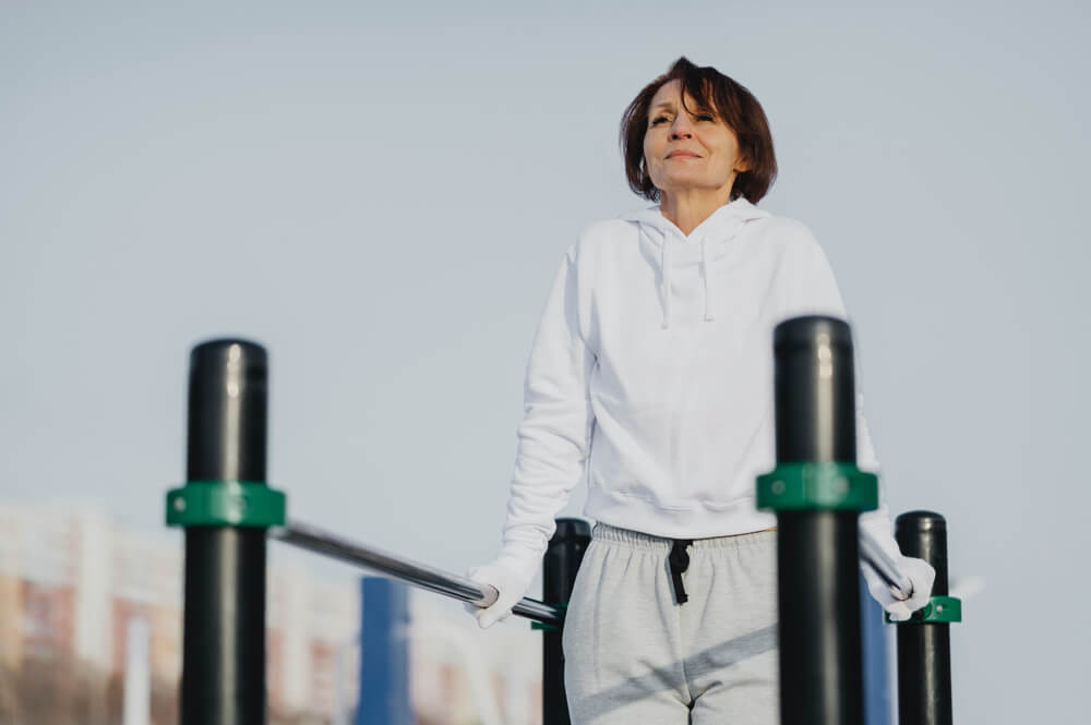 woman working out at park in winter weather wearing a hoodie.