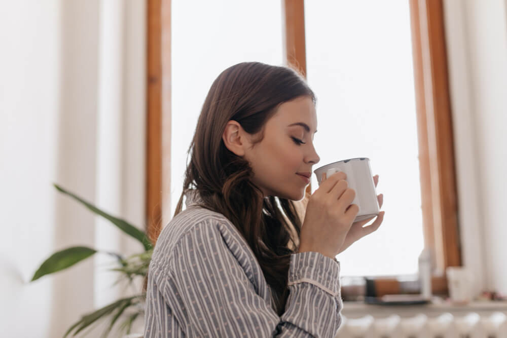 Close-up of a woman's hand with disposal cup off coffee using laptop and studying 
