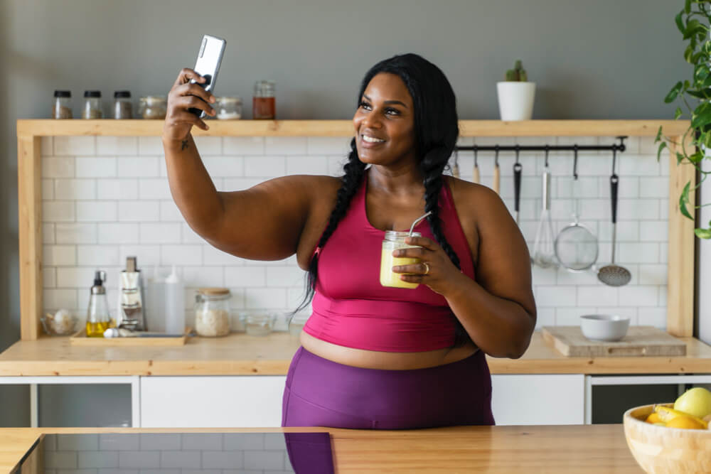 Medium shot black woman relaxing at home drinking weight loss detox drink