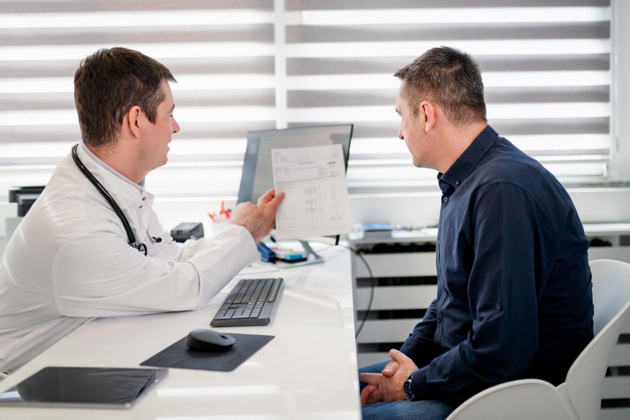 Doctor explaining elevated PSA blood test results to a male patient during a prostate health consultation.